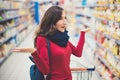 Portrait of young beatiful brunette woman looking surprised at the shelf