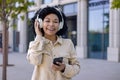 Portrait of young beautiful African American woman, student smiling and looking at camera holding phone in hands using Royalty Free Stock Photo