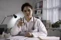 Portrait of young beautiful Asian female doctor looking at camera in medical office, having online consultation with patient. Youn Royalty Free Stock Photo