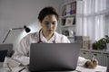 Portrait of young beautiful Asian female doctor working with laptop computer in medical office, having online consultation with pa Royalty Free Stock Photo