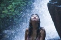 Portrait of young beautiful Asian girl looking pure and enjoying nature beauty with face wet under amazing beautiful natural water Royalty Free Stock Photo