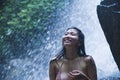 Portrait of young beautiful Asian girl looking pure and enjoying nature beauty with face wet under amazing beautiful natural water Royalty Free Stock Photo