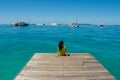 Portrait of young beautiful asian girl sitting at the pier looking at the ocean