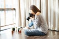 Portrait of young beautiful Asian girl use DSLR camera to take photo of cactus on the floor in living room at her home. Making