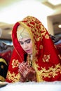 Portrait of young and beautiful Asian muslim bride wearing traditional dress sitting with hands praying gesture and eyes closed Royalty Free Stock Photo