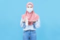 Portrait of young beautiful asian muslim woman  in traditional dress wearing medical face mask holding Alcohol Spray Bottle Royalty Free Stock Photo