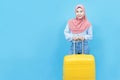 Portrait of young beautiful asian muslim woman in traditional dress with yellow suitcase or luggage  isolated on blue background, Royalty Free Stock Photo