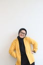 portrait of young beautiful Asian Muslim woman, wearing glasses and yellow blazer with happy smiling face expression Royalty Free Stock Photo