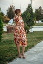 Portrait of a young beautiful Asian skinny slender woman in a floral print dress standing outside during sunset Royalty Free Stock Photo