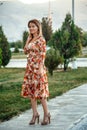 Portrait of a young beautiful Asian skinny slender woman in a floral print dress standing outside during sunset Royalty Free Stock Photo