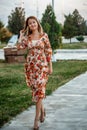 Portrait of a young beautiful Asian skinny slender woman in a floral print dress standing outside during sunset Royalty Free Stock Photo