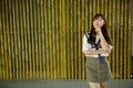 Young beautiful Asian teenage girl thinking against bamboo fence Royalty Free Stock Photo