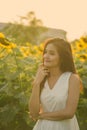 Young beautiful Asian woman thinking in the field of blooming sunflowers Royalty Free Stock Photo