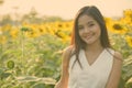 Young happy beautiful Asian woman smiling in the field of blooming sunflowers Royalty Free Stock Photo