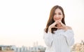 Portrait of young beautiful asian woman hands gesture in heart shape on city sky roof top. Royalty Free Stock Photo