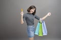 Portrait of young beautiful asian woman holding credit card and colorful shopping bag isolated over gray background studio Royalty Free Stock Photo