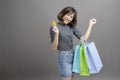 Portrait of young beautiful asian woman holding credit card and colorful shopping bag isolated over gray background studio Royalty Free Stock Photo