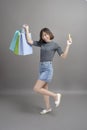 Portrait of young beautiful asian woman holding credit card and colorful shopping bag isolated over gray background studio Royalty Free Stock Photo