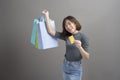 Portrait of young beautiful asian woman holding credit card and colorful shopping bag isolated over gray background studio Royalty Free Stock Photo