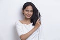 Young beautiful asian woman looking at the camera and combing long hair with a comb isolated on white background Royalty Free Stock Photo