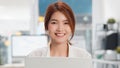 Portrait of young beautiful Asian woman looking at camera and smile, using laptop computer in home office Royalty Free Stock Photo