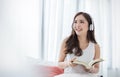 Portrait of young beautiful asian woman relax holding book listen to music from headphone in bedroom. Royalty Free Stock Photo