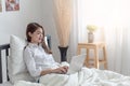 Young Asian woman relaxing and lying in bed at home with use the laptop computer in bedroom Royalty Free Stock Photo