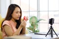 Portrait of young beautiful asian woman sitting on a floor smiling while showing how to make origami paper via smartphone. Work Royalty Free Stock Photo