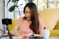 Portrait of young beautiful asian woman sitting on a floor smiling while working communicating via smartphone in a living room at Royalty Free Stock Photo