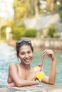 Portrait of a beautiful Asian woman drinking a pineapple cocktail in the pool Royalty Free Stock Photo