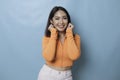 Portrait of Young beautiful Asian woman standing and smiling at the camera, isolated on blue background Royalty Free Stock Photo