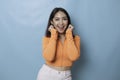 Portrait of Young beautiful Asian woman standing and smiling at the camera, isolated on blue background Royalty Free Stock Photo