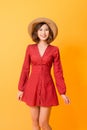 Portrait of young beautiful asian woman  wear red dress and hat over orange background. Summer concept Royalty Free Stock Photo