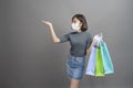 Portrait of young beautiful asian woman wearing a surgical mak is holding credit card and colorful shopping bag isolated over gray Royalty Free Stock Photo