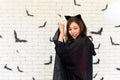 Portrait of young beautiful asian woman wearing witch costume posing with balloons on white brick background Royalty Free Stock Photo