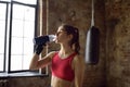 Portrait of young beautiful athlete in a boxing gym. A boxer girl drinking beverage from a bottle during a workout. In the process Royalty Free Stock Photo