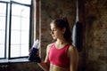 Portrait of young beautiful athlete in a boxing gym. A boxer girl drinks beverage from a bottle during a workout. In the process Royalty Free Stock Photo