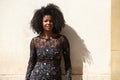 Portrait of a young, beautiful black woman with afro hair and a black dress with flowers with a sad and serious expression. In the Royalty Free Stock Photo