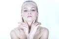 Portrait of young beautiful blond model with nude make up, slicked back hair and naked shoulders holding her hands crossed at face Royalty Free Stock Photo