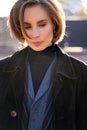 Young blond short-haired woman in velvet coat, vest and sweater on sunny street Royalty Free Stock Photo