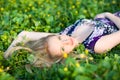 Portrait of young beautiful blond woman lying in grass and flowers on summer day with green nature landscape Royalty Free Stock Photo