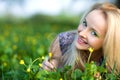 Portrait of young beautiful blond woman lying in grass and flowers on summer day with green nature landscape Royalty Free Stock Photo