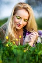 Portrait of young beautiful blond woman lying in grass and flowers on summer day with green nature landscape Royalty Free Stock Photo