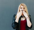 Portrait of a young beautiful blonde girl closes mouth her hands in surprise