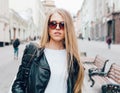 Portrait of a young beautiful blonde girl with sunglasses walking on the streets of Europe. Outdoor. Warm color.