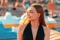 Portrait of a young beautiful blonde smiling woman in the sun. In the background, the beach is in a blur Royalty Free Stock Photo