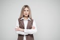 Portrait of a young beautiful blonde woman on a gray background in a business brown suit. Royalty Free Stock Photo