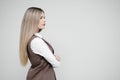 Portrait of a young beautiful blonde woman on a gray background in a business brown suit. Royalty Free Stock Photo