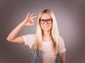 Portrait of young beautiful blonde woman who showing sign `cool` and smiling against the grey background Royalty Free Stock Photo