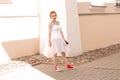 Portrait of a young beautiful bride in red sneakers with bouquet of roses on the city street. Royalty Free Stock Photo